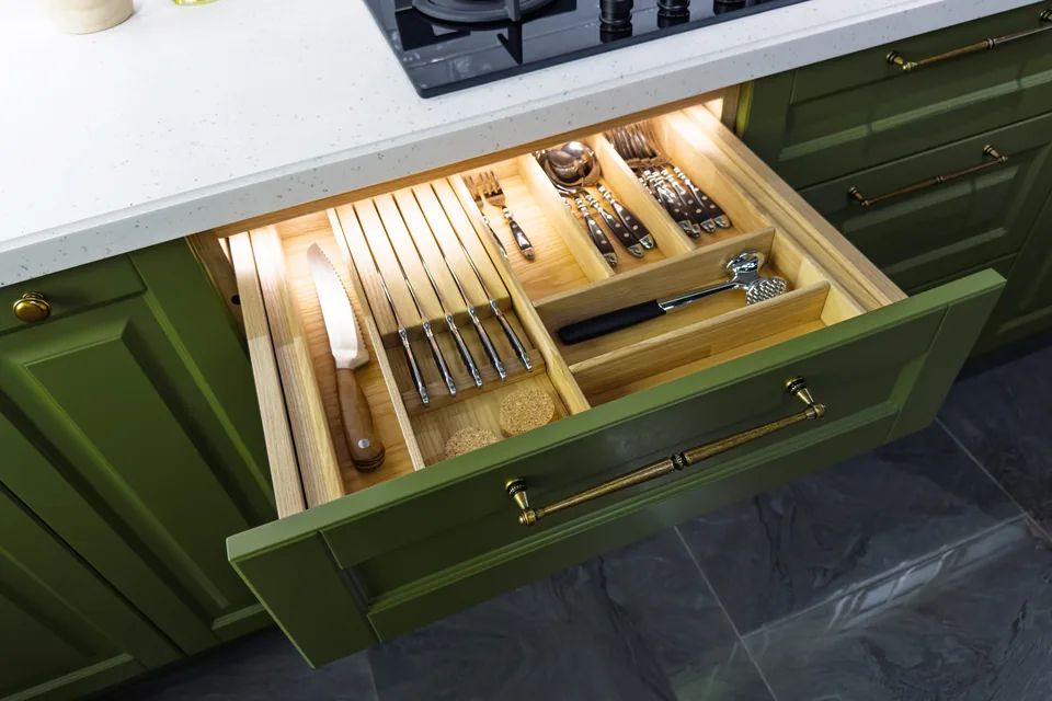 Lit oak cutlery drawer in an olive green kitchen